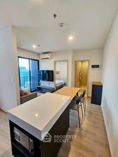 Modern open-plan living room with kitchen island and city view balcony in stylish apartment.