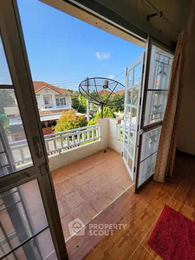 Charming balcony view with open doors and sunny neighborhood scenery.