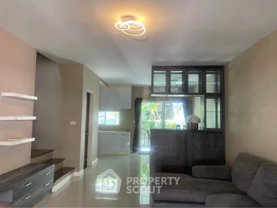 Modern living room with sleek furniture and open layout, featuring a stylish staircase and elegant lighting.