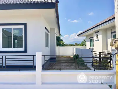 Modern single-story house with white exterior and fenced yard in a serene neighborhood.