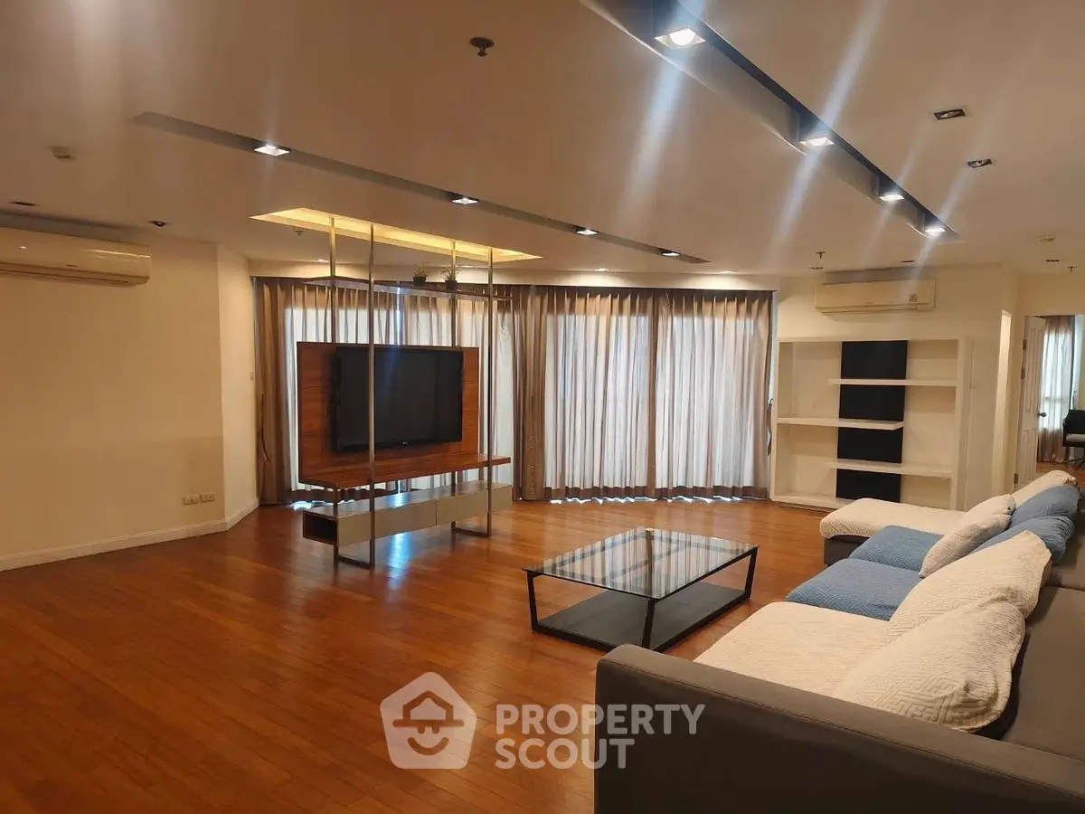 Spacious modern living room with wooden flooring and large windows for natural light.