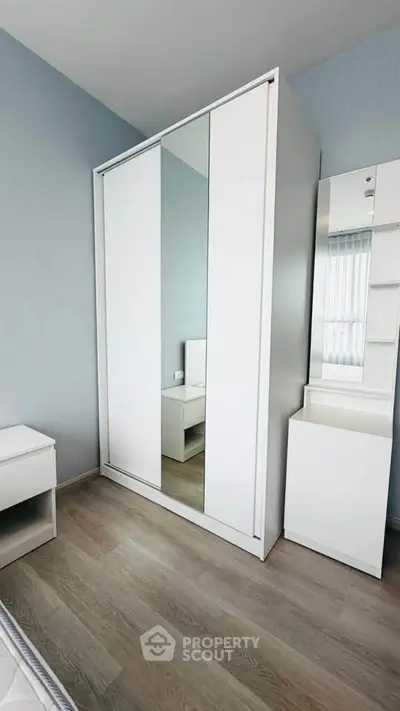 Modern bedroom with sleek white wardrobe and wooden flooring