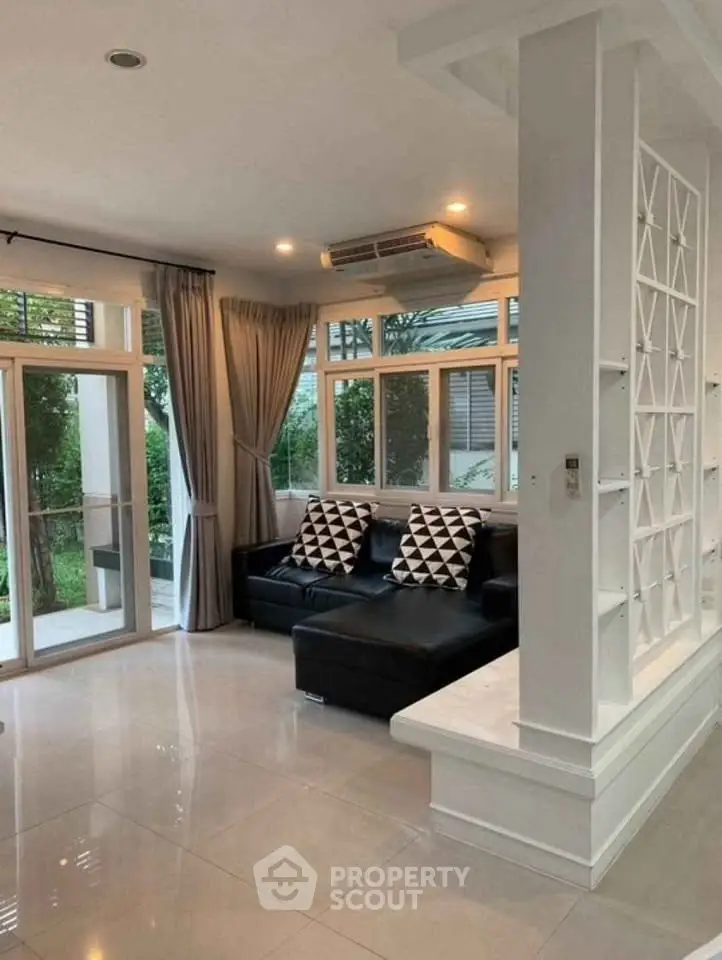 Spacious living room with modern decor and large windows overlooking garden.