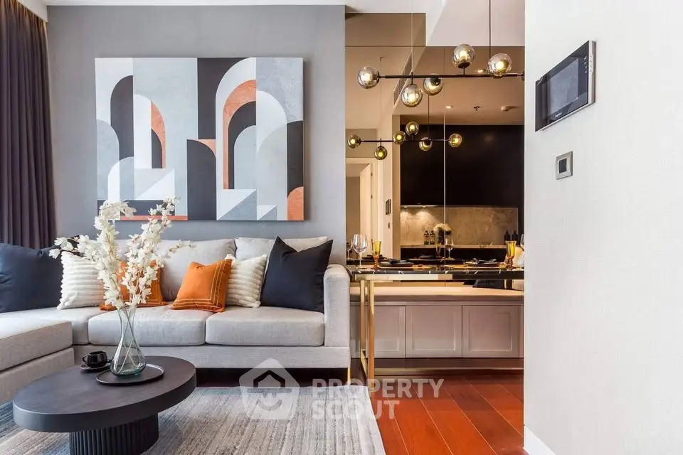 Modern living room with stylish decor and open kitchen layout, featuring elegant lighting and contemporary artwork.