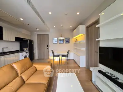 Modern living room with open kitchen, leather sofa, and stylish dining area in a contemporary apartment.
