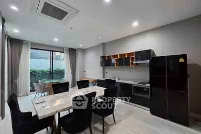 Modern open-layout kitchen and dining area with sleek black appliances and elegant dining table.