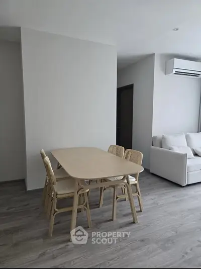Modern living room with dining area and air conditioning, featuring sleek wooden flooring and minimalist furniture.