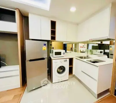Modern kitchen with sleek appliances including fridge, washing machine, and microwave in compact layout.