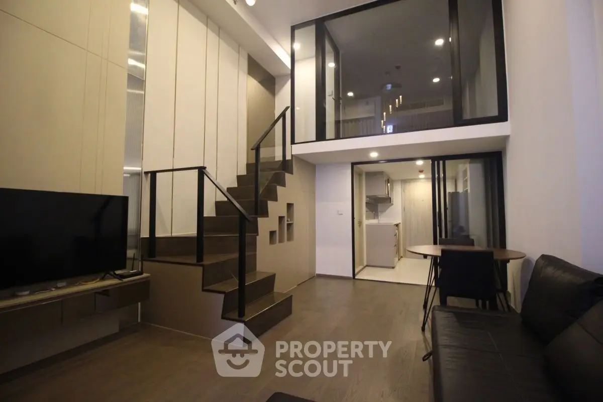 Modern duplex living room with sleek staircase and open kitchen layout