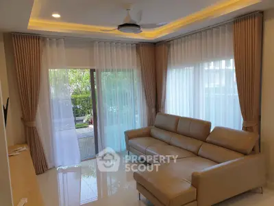 Elegant living room with modern leather sofa and large windows overlooking a lush garden.