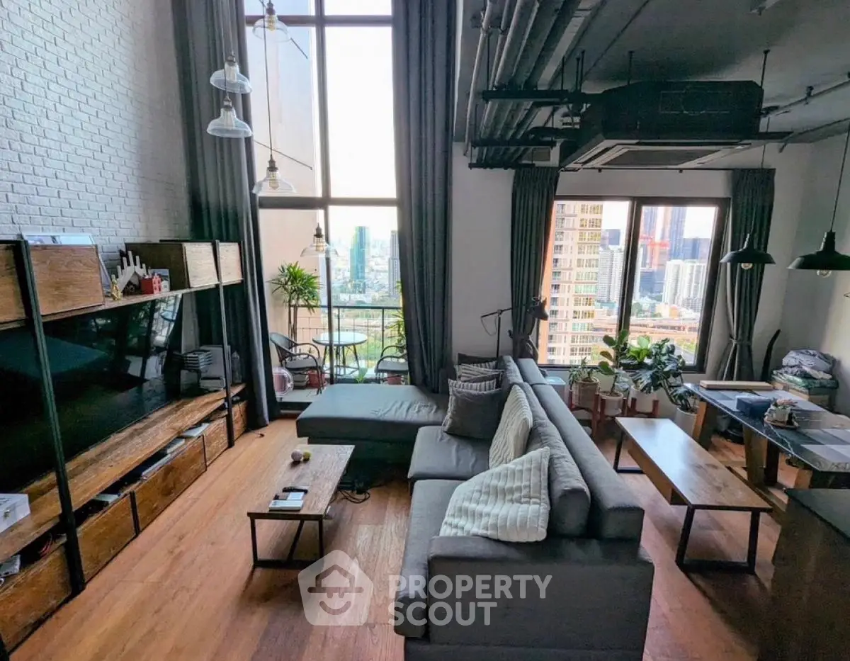Modern living room with high ceilings and city view, featuring stylish furniture and large windows.