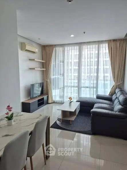 Modern living room with leather sofa and large windows in high-rise apartment