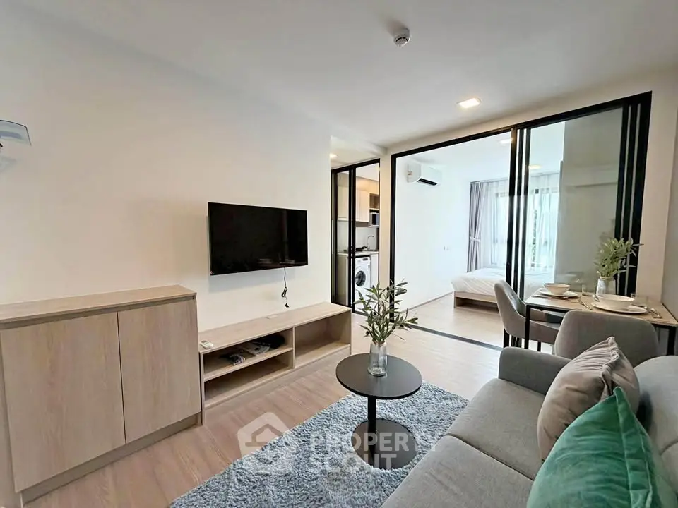 Modern living room with open layout, stylish furniture, and view into a cozy bedroom