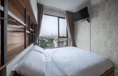 Cozy bedroom with city view, featuring modern decor and large window for natural light.