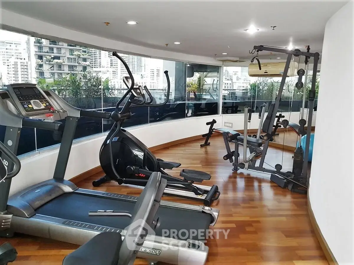Modern gym with city view, featuring treadmill and exercise equipment, ideal for fitness enthusiasts.