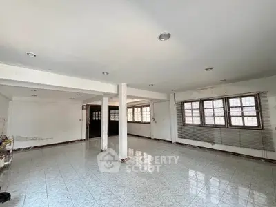 Spacious open-plan living area with tiled flooring and large windows for natural light.