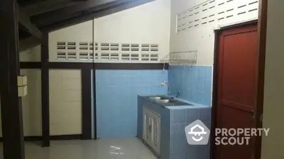 Compact kitchen space with blue tile backsplash, wooden beams, and a convenient sink area, ideal for efficient urban living.