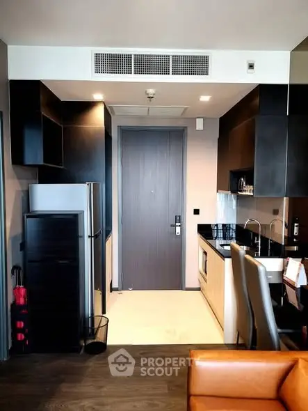 Modern kitchen with sleek black cabinets and stainless steel appliances in a stylish apartment.