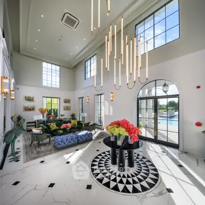 Luxurious living room with high ceilings, modern chandelier, and pool view, perfect for upscale living.