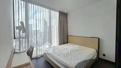 Modern bedroom with large window and city view, featuring a comfortable bed and sleek design.