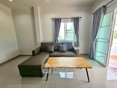 Modern living room with sleek sofa and wooden coffee table, featuring natural light from large windows.