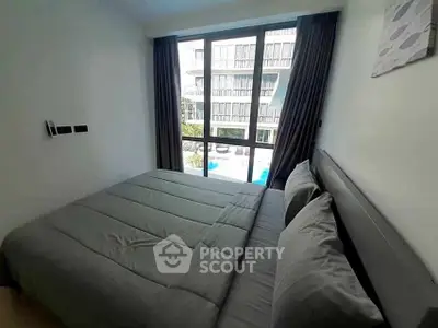 Cozy bedroom with large window offering a pool view in modern apartment.