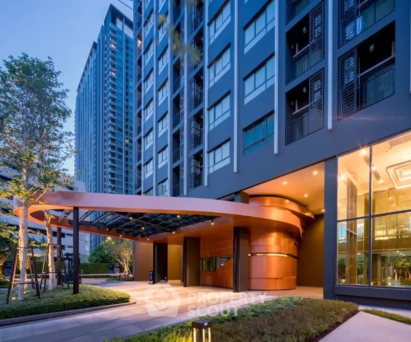 Modern building entrance with sleek design and lush landscaping