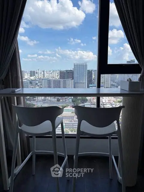 Stunning city view from modern high-rise apartment with floor-to-ceiling windows and stylish seating area.