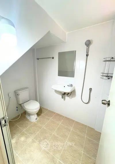 Modern bathroom with sleek fixtures and neutral tiles, featuring a shower and compact design.