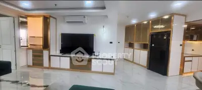 Luxurious modern living room with sleek gold accents and spacious layout, featuring a large TV and elegant cabinetry.