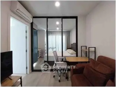 Modern studio apartment with glass partition, cozy seating, and natural light.