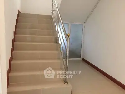 Modern staircase with sleek metal railing in a minimalist interior space.