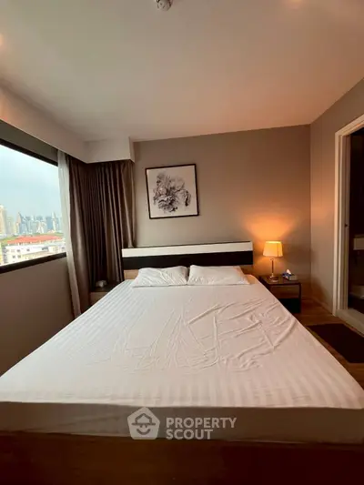 Cozy bedroom with city view, featuring a large bed and modern decor, perfect for urban living.