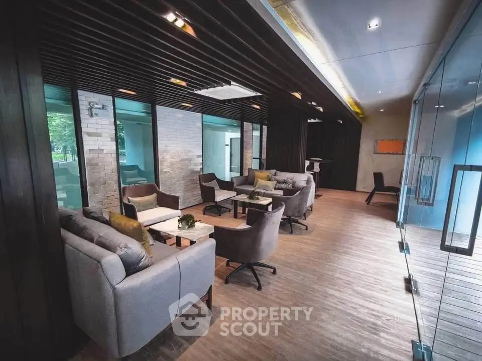 Modern co-working space with stylish seating and glass partitions in a contemporary building.