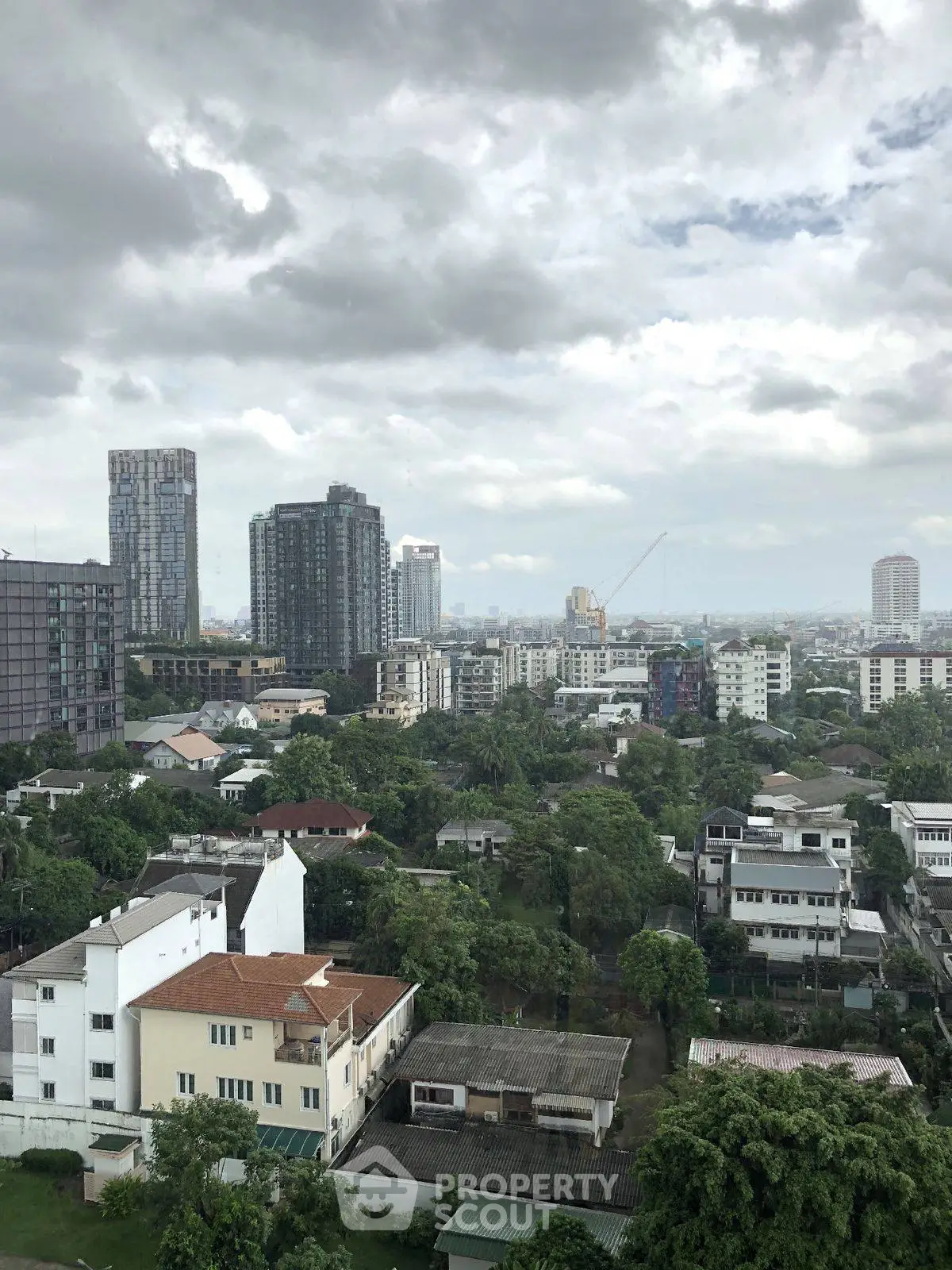 Stunning cityscape view from a high-rise building showcasing urban skyline and lush greenery.