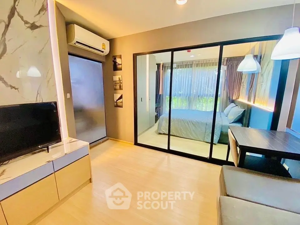 Modern apartment interior with open layout, featuring a cozy living area and stylish bedroom separated by glass doors.