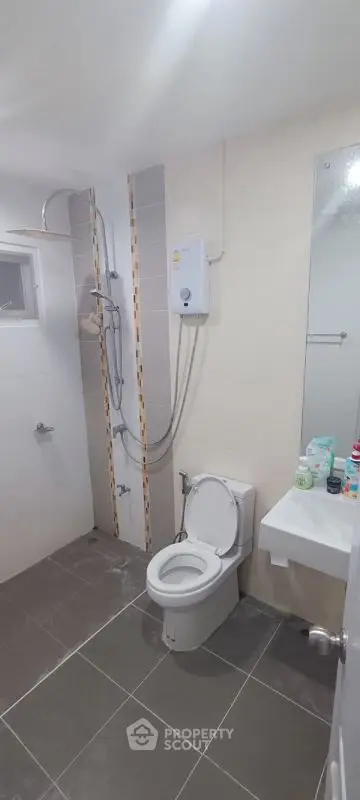 Modern bathroom with shower, toilet, and sink in sleek design.