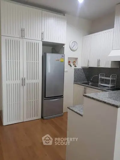 Modern kitchen with sleek cabinets and stainless steel fridge in cozy apartment.