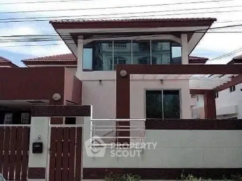Modern two-story house with large windows and red roof, showcasing contemporary architecture.