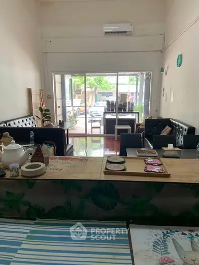 Charming living room with cozy seating and large glass doors opening to a lush garden view.