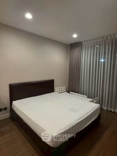 Spacious bedroom with modern decor and large window for natural light.