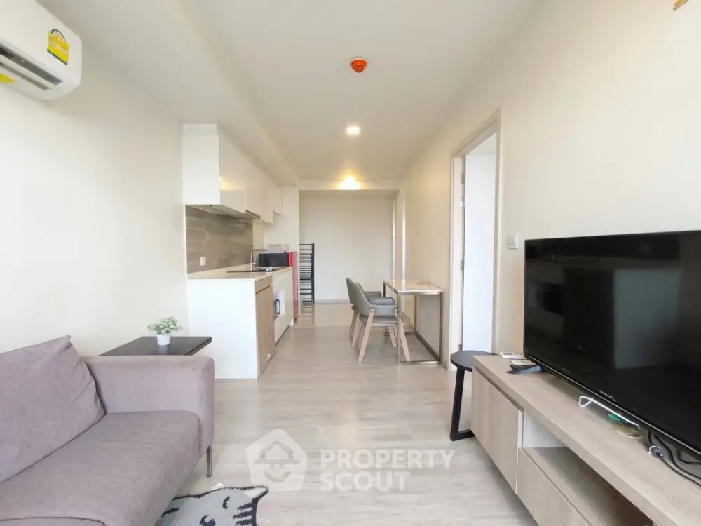 Modern open-plan living room and kitchen with sleek furniture and neutral tones.