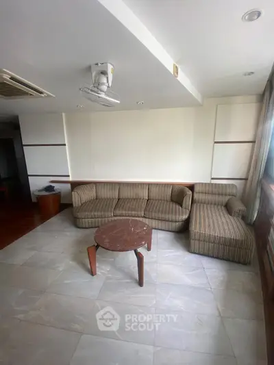 Spacious living room with modern striped sofa and round coffee table, perfect for relaxation.
