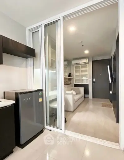 Modern apartment interior with sliding glass doors and compact fridge