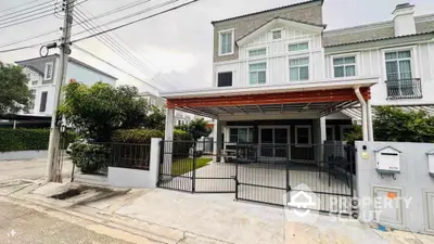 Modern townhouse with gated entrance and carport in a serene neighborhood.