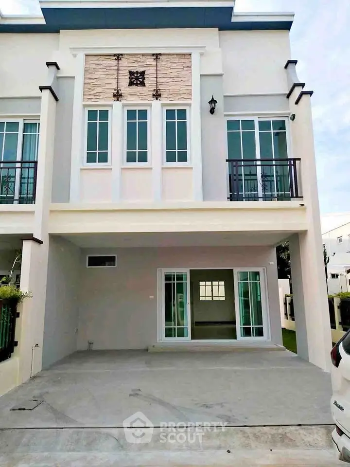 Modern two-story townhouse with large windows and spacious driveway in a serene neighborhood.