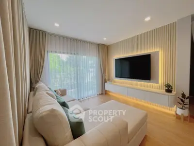 Modern living room with large TV and cozy sofa, featuring elegant curtains and wooden flooring.