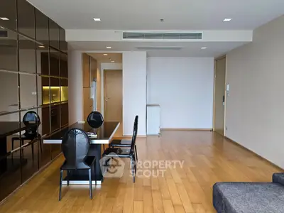 Spacious modern living room with wooden flooring and sleek dining area in a contemporary apartment.