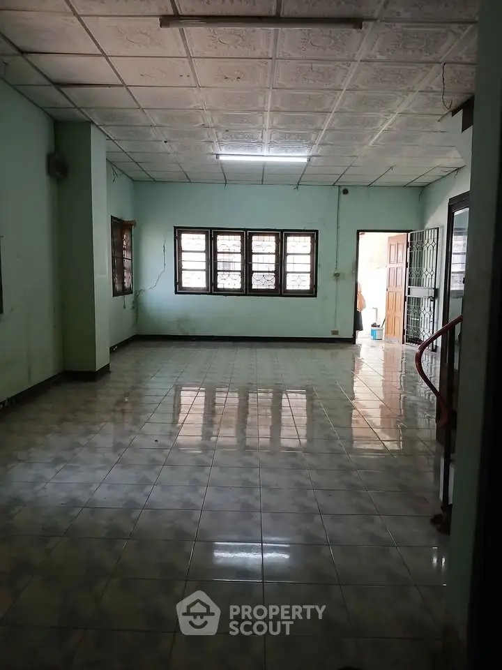 Spacious empty room with tiled floor and large windows, ideal for customization.