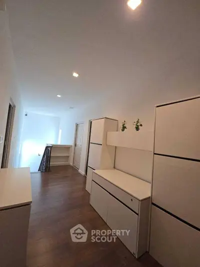 Spacious hallway with modern white cabinetry and wooden flooring, perfect for storage solutions.